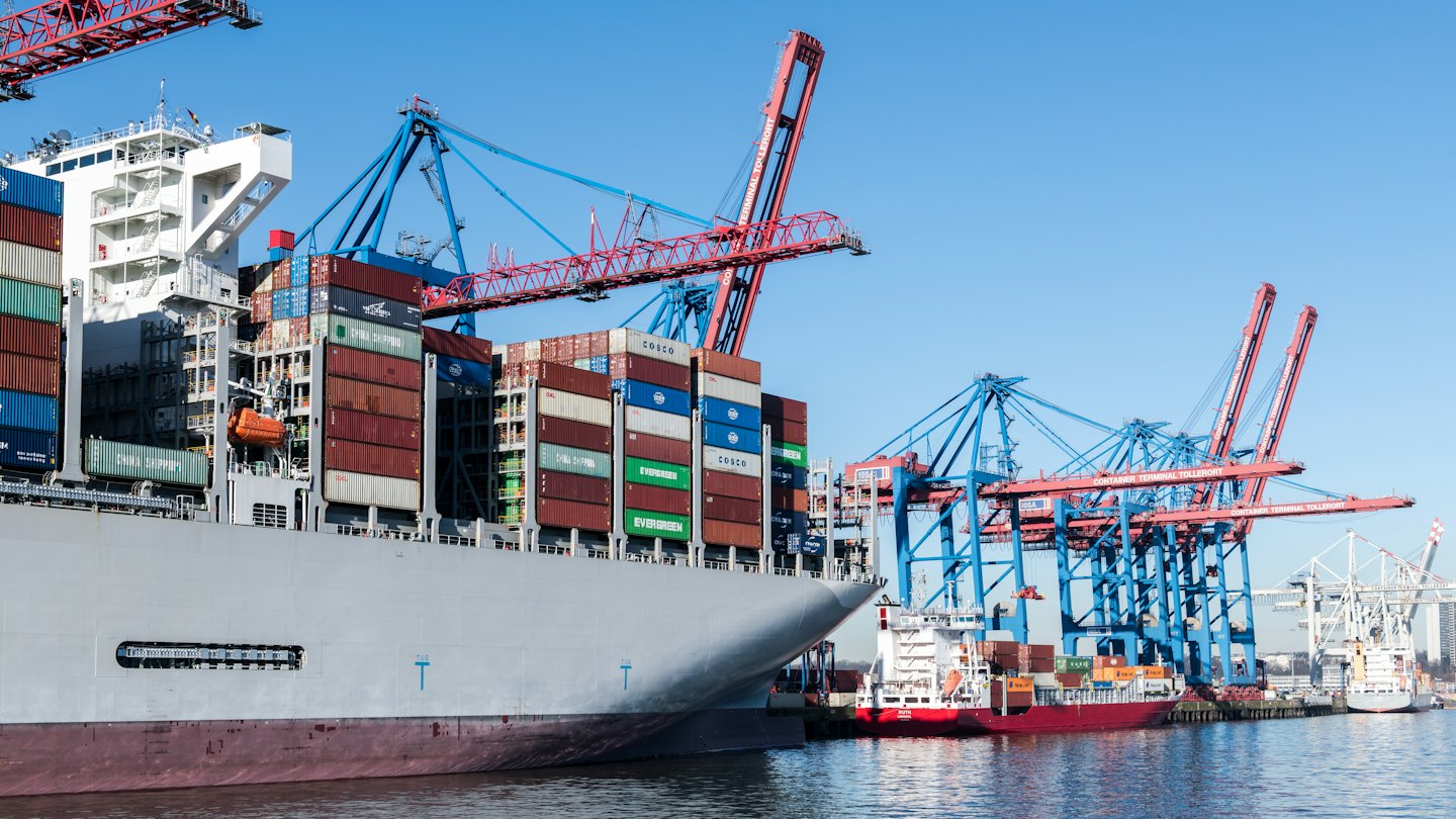 A large container ship docked at a busy industrial port.