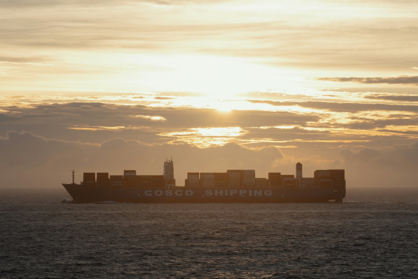 A large cargo ship sails across the open ocean.