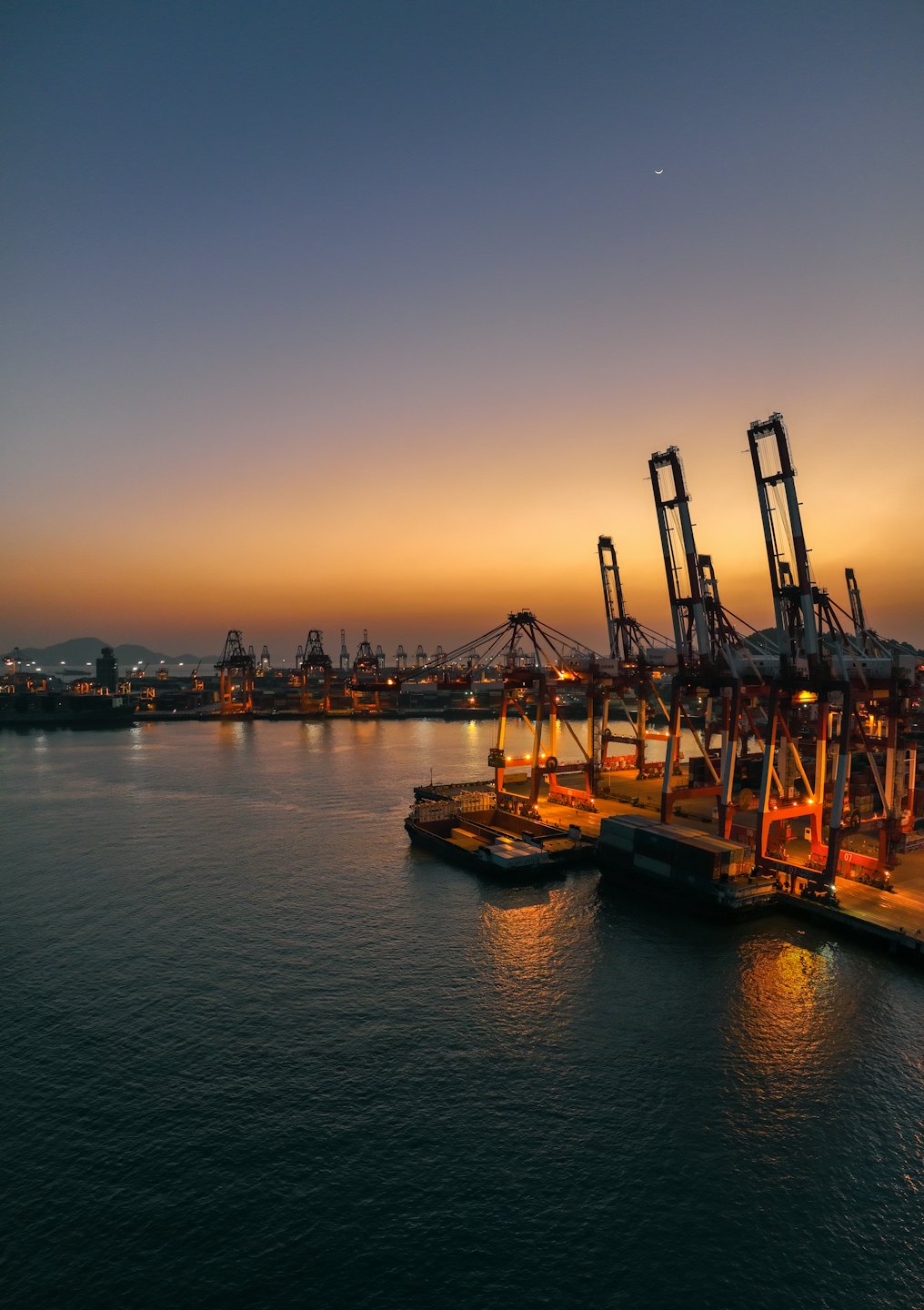 Cargo ship docked at a busy port with many cranes.